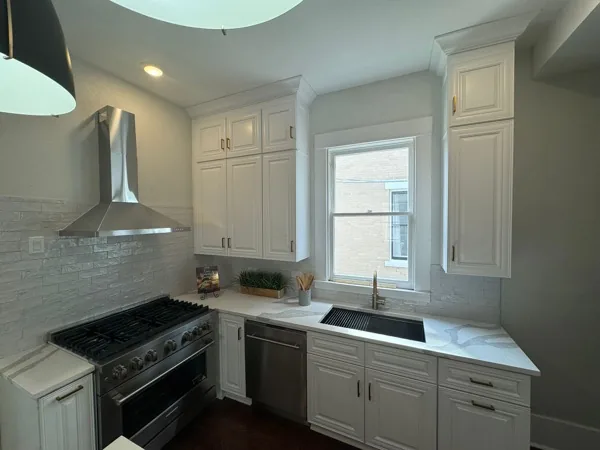 White shaker kitchen with vent hood and farmhouse sink by WoodArt Cabinets San Antonio
