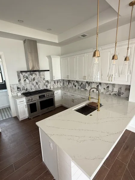 White kitchen with marble waterfall island and pendant lights by WoodArt Cabinets San Antonio